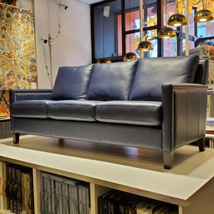custom sofa done in blue genuine leather with pewter nail heads on the inside and outside arms