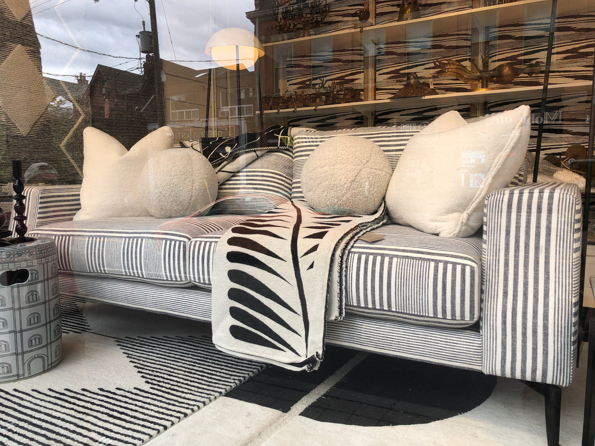 grey and white striped sofa with white pillows and throw blanket