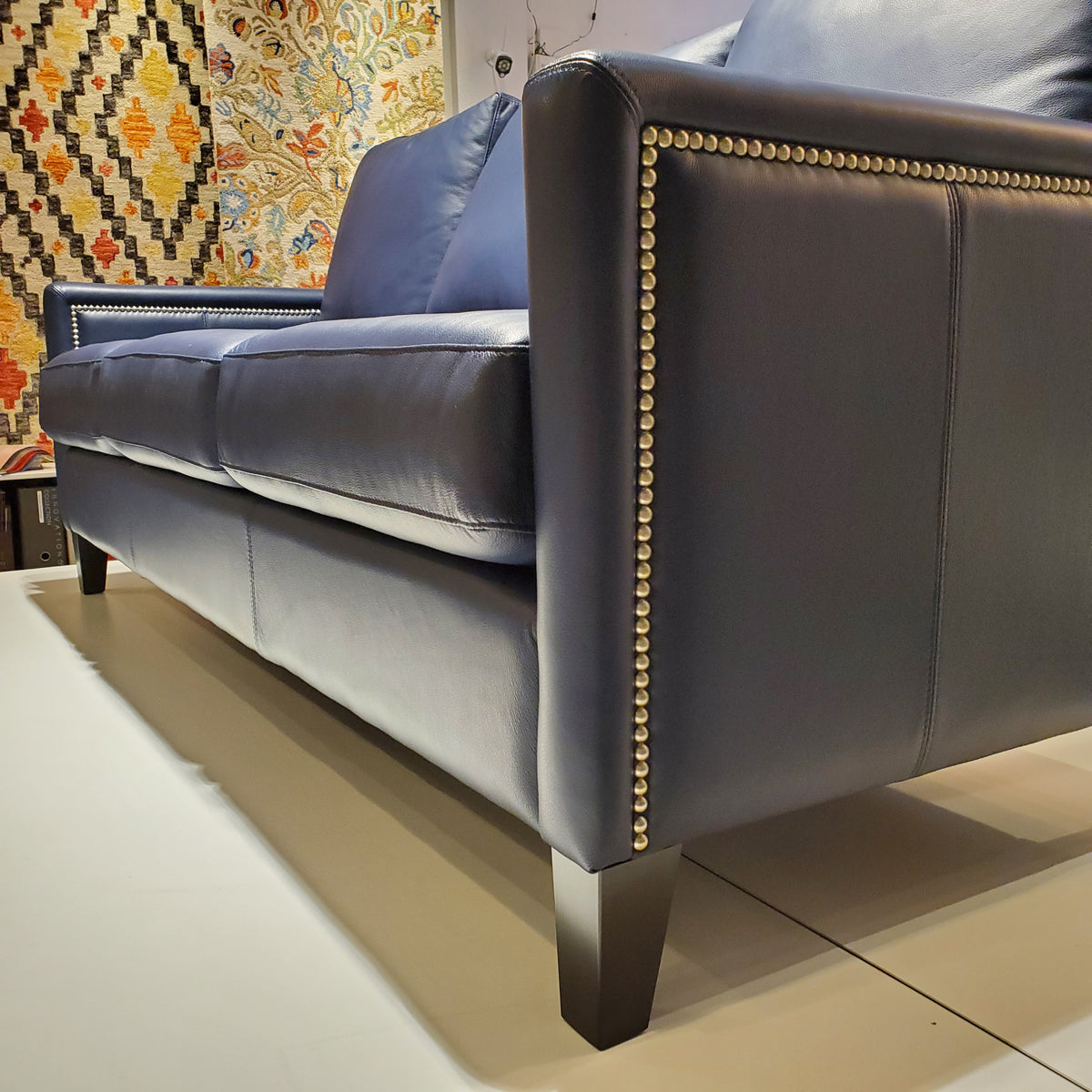 close up of custom sofa done in blue genuine leather with pewter nail heads on the inside and outside arms