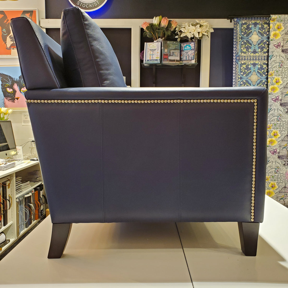 side view of custom sofa done in blue genuine leather with pewter nail heads on the inside and outside arms