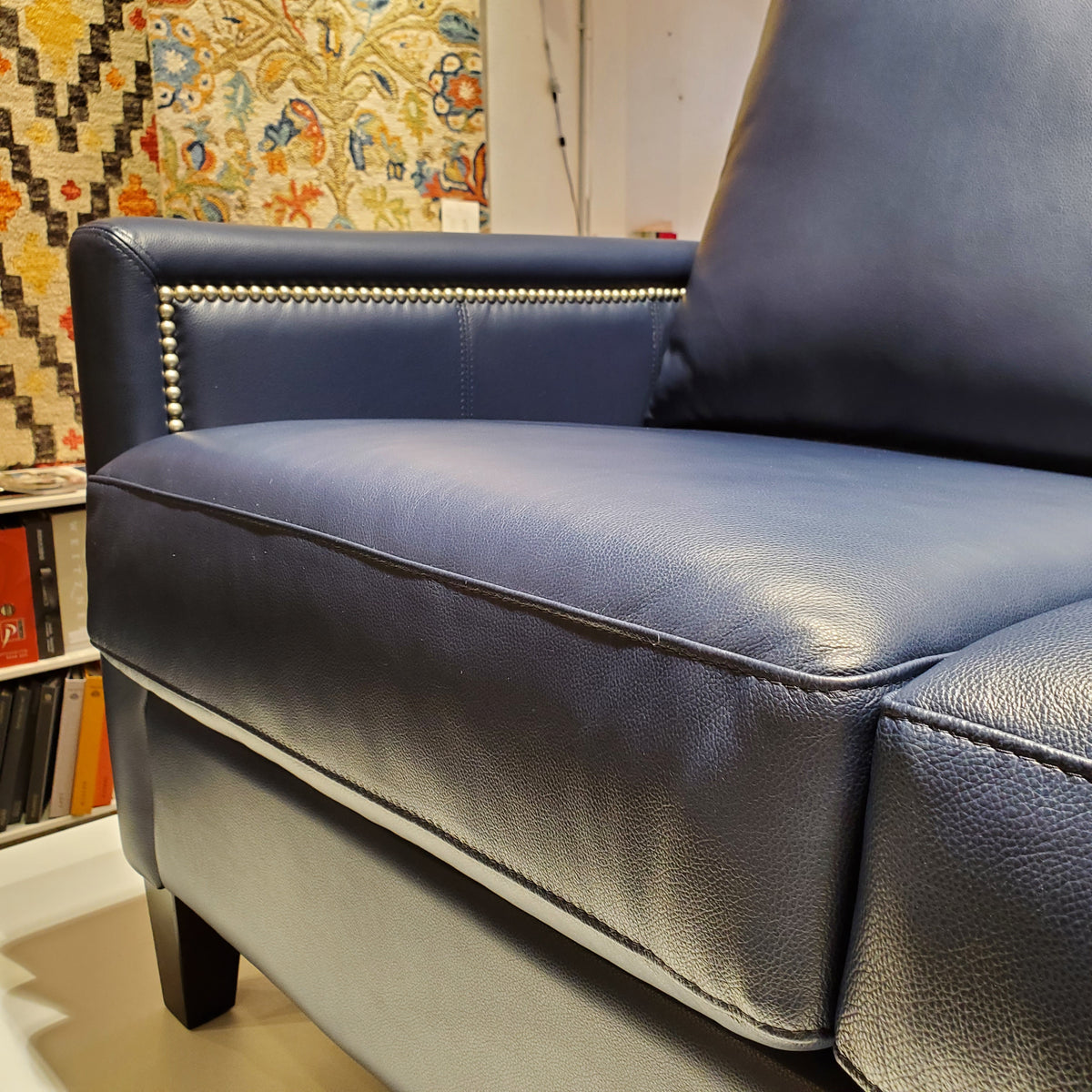 close up of custom sofa done in blue genuine leather with pewter nail heads on the inside and outside arms