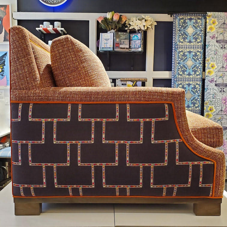 custom sofa in stain-resistant nubbly textured fabric, contrast embroidered fabric on the arms and orange velvet piping